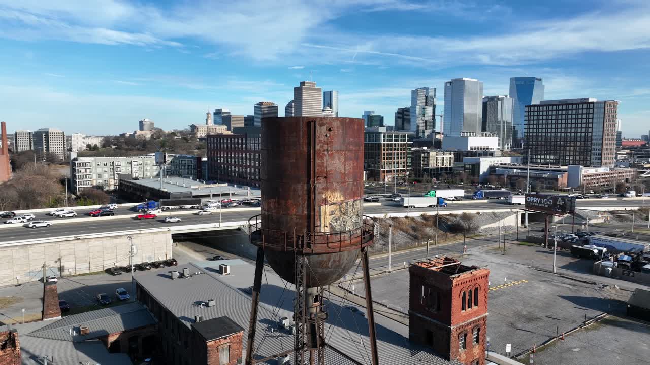 Vue aérienne d’un château d’eau historique rouillé à Marathon Motor Works à Nashville, dans le Tennessee, avec la ligne d’horizon du centre-ville et la circulation autoroutière en arrière-plan. Reconversion urbaine et patrimoine industriel aux États-Unis