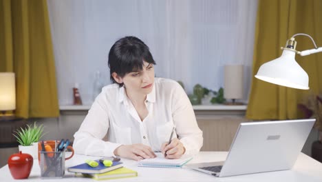 female student working between paper and laptop.