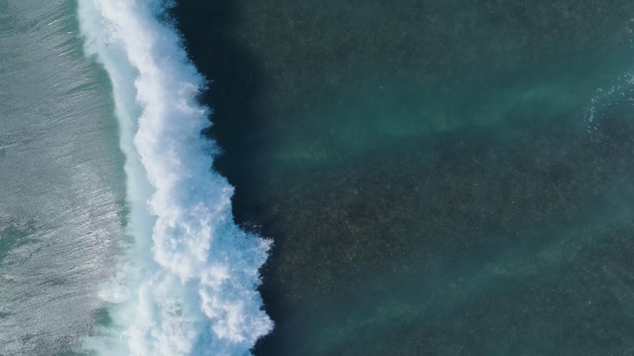 Top Down Slow Motion Drone shot of wave action over coral reef in Uluwatu Bali Indonesia