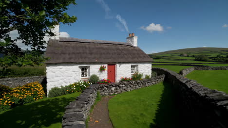 Picturesque Thatched Cottage with Red Door and Vibrant Flowers in a Rural Setting