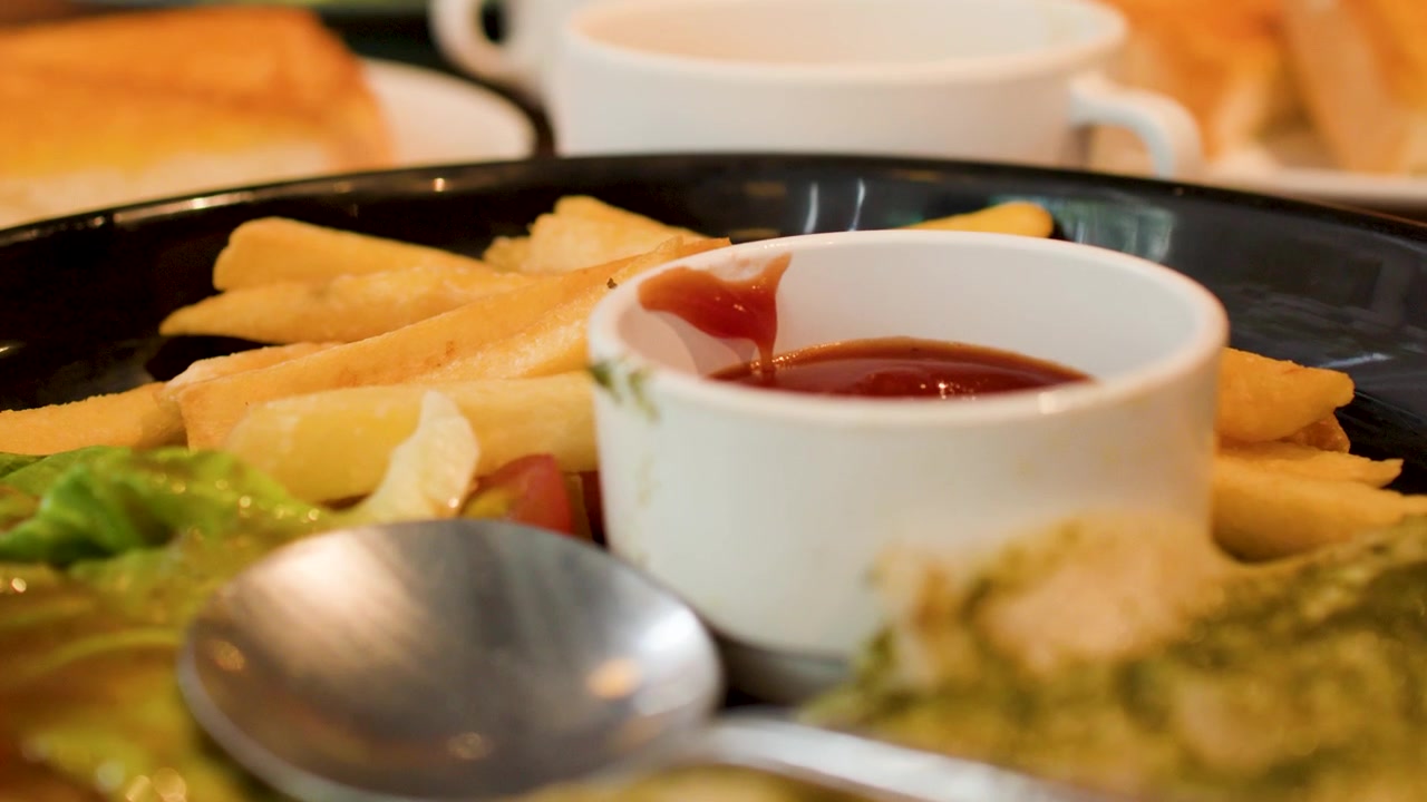 Un primo piano si concentra su patatine fritte, ketchup e insalata durante un pranzo al ristorante