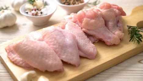 fresh raw chicken wings on wooden board with ingredients