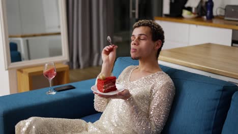 a man in a dress sitting on a sofa, admires a piece of cake