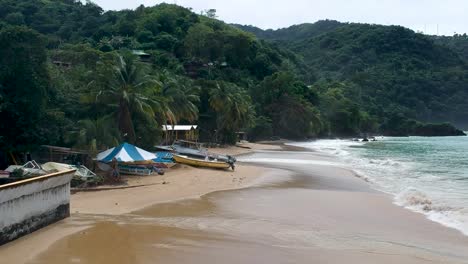 Niedrig-Fliegende-Drohnenaufnahme-Einer-Blutigen-Bucht-Mit-Strand,-Booten-Und-Bergen-Im-Hintergrund-Auf-Der-Insel-Tobago