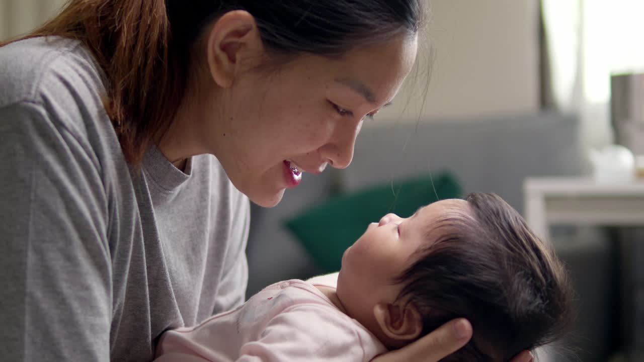 새로 태어난 아이를 품에 안고 잠들게 하기 위해 잠자리 노래를 부르면서 미소 짓고 있습니다.