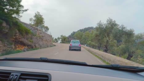 A-drive-in-Sant-Llorenç-road-showing-traditional-Mallorcan-village-greenery,-following-a-car-Mallorca,-Spain