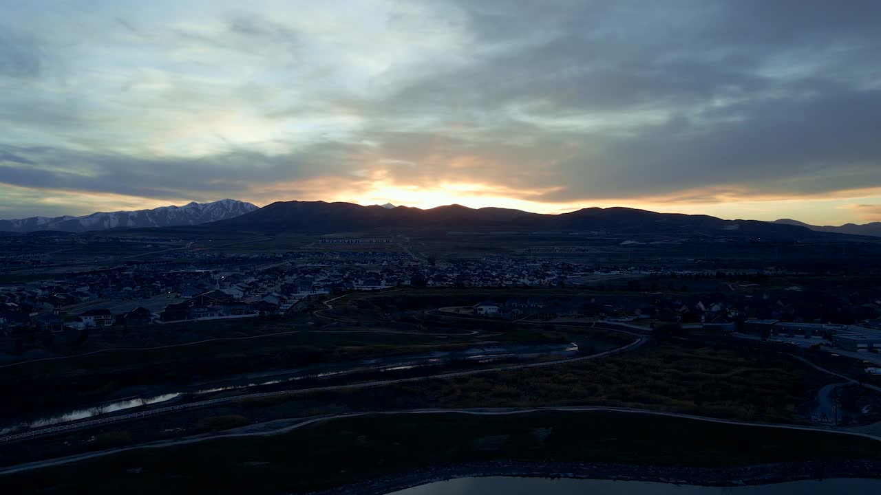 una comunidad suburbana debajo de las montañas al atardecer - vista aérea deslizante del vecindario, el río y el campo de golf