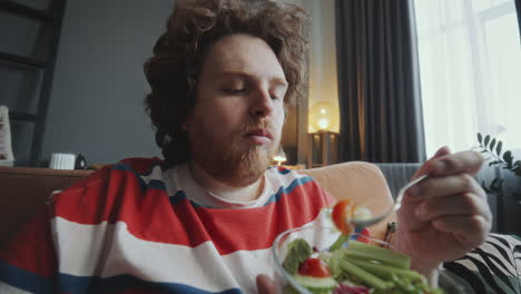 man eating salad on couch