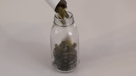 una pequeña botella de vidrio está llena de cápsulas de pastillas de color marrón dorado