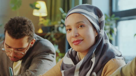 portrait of cheerful muslim woman in hijab studying in school for immigrants
