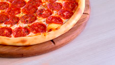 half of salami pizza on wooden board on the table.