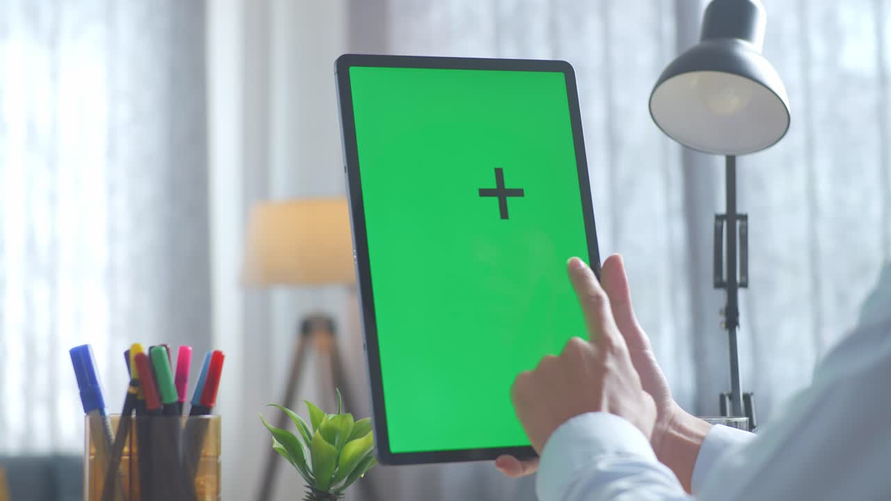 녹색 화면을 가진 태블릿을 사용하는 사람