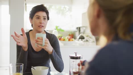 Caucasian-woman-talking-to-her-wife-while-having-breakfast-at-home