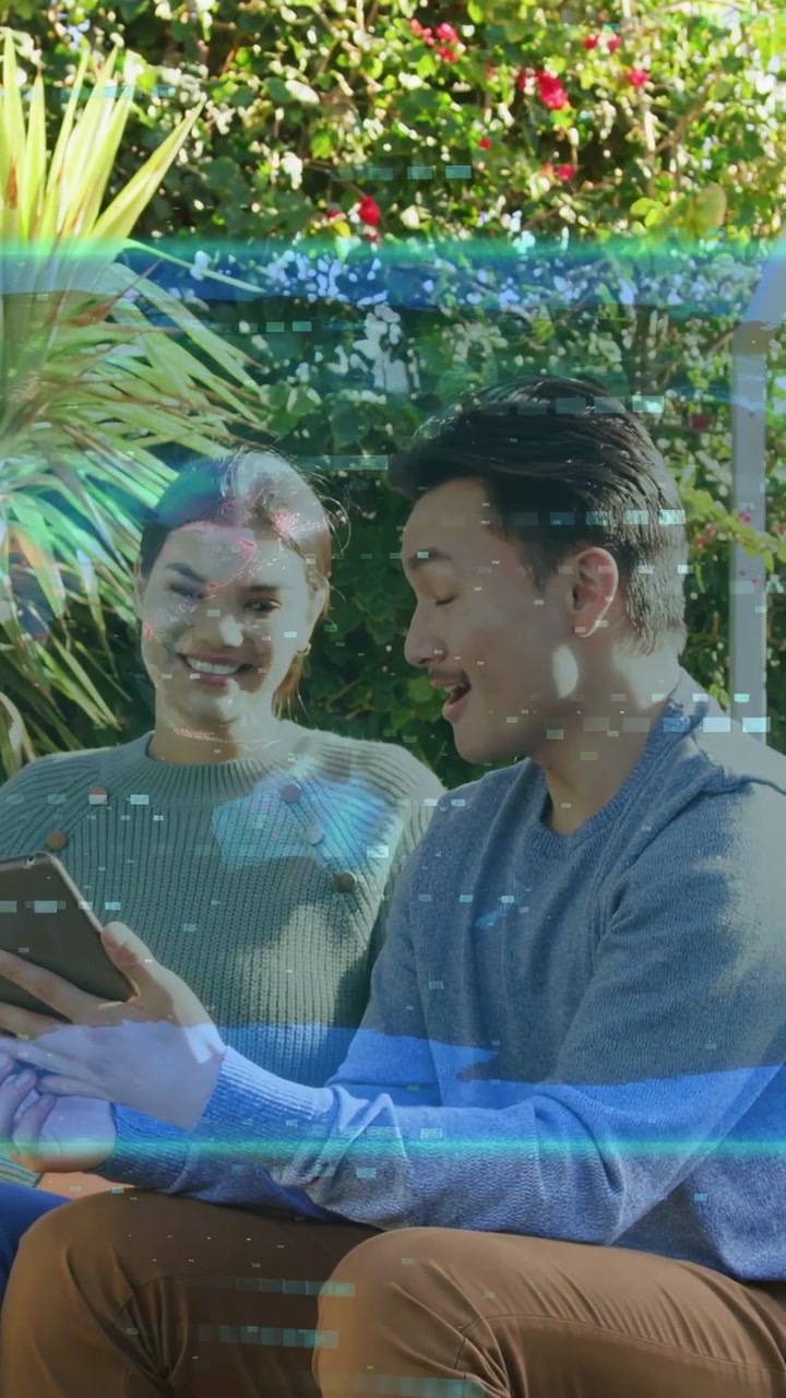 Video verticale: Uomo che tiene un tablet e dimostra tecnologia, donna che si appoggia sorridendo con un effetto glitch blu sui volti.