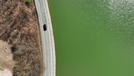 Follow-footage-of-black-luxury-wedding-car-driving-on-country-road-and-the-lake-on-the-side-during-autumn-sunny-afternoon