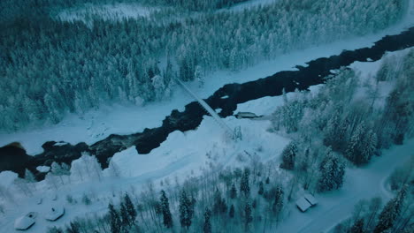 fly over winter forest and river scenery in vikakongas finland - aerial shot