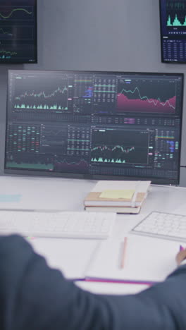 Multi-ethnic-team-of-traders-work-on-multi-monitor-computers-with-displayed-real-time-stocks.-Colleagues-analyze-exchange-market-charts-on-big-screens.-Cryptocurrency-trading-and-investment-concept.