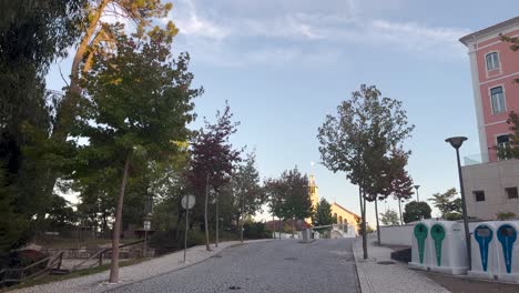 captura diurna de la calle vacía de la ciudad con bajo ángulo de luz solar, área de paseo del parque con árboles en un lado y edificio residencial en el otro