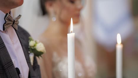 newlyweds. caucasian bride and the groom stand in church with candles at wedding ceremony