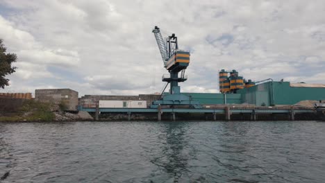 grúa portuaria en la instalación industrial a lo largo del río en el parque nacional de biesbosch visto desde un velero en países bajos