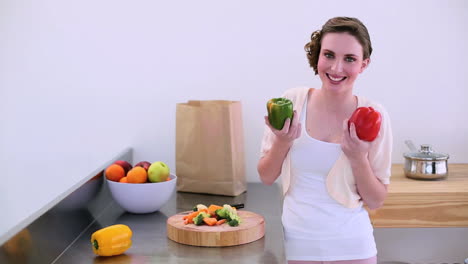 Pretty-model-standing-in-kitchen-taking-peppers-from-paper-bag