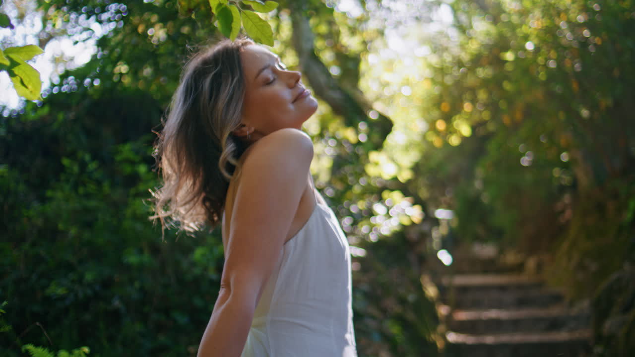 Primo piano di una ragazza romantica che passeggia sulle scale di un parco godendosi la bellezza e la tranquillità della natura estiva