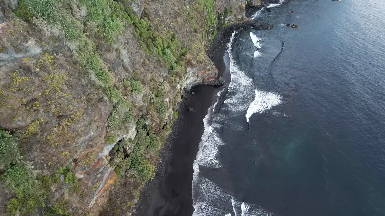 Drone aerial view of waves crashing against the black sand beach of Nogales, La Palma, on the Canary Islands coastline cliffs