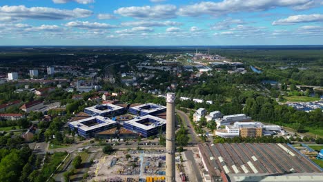 hennigsdorf steel industry with industrial buildings, chimneys, storage area and a river in the background. lovely aerial view flight fly reverse drone