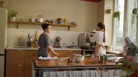 two women are working together in a bakery kitchen preparing and baking.