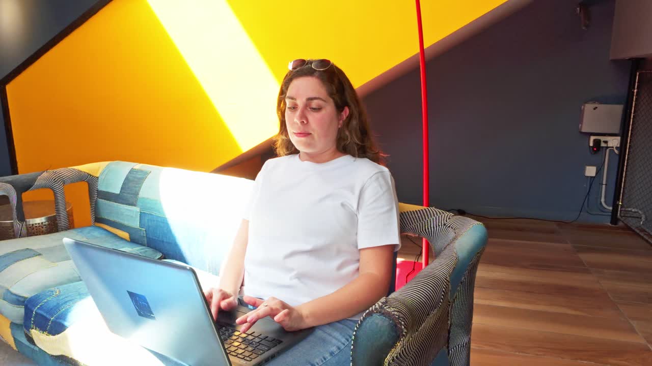 Donna che lavora da remoto al portatile in una moderna lobby di coworking