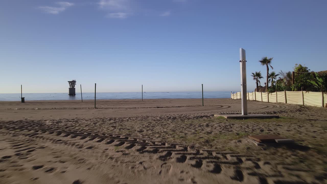 바다에 버려진 오버헤드 케이블 타워가 있는 스페인 마르베야의 빈 해변에서 앞으로 나아갑니다.