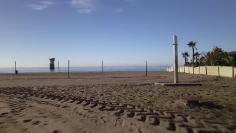 avanzando en la playa vacía de marbella, españa, con una torre de cable aérea abandonada en el mar