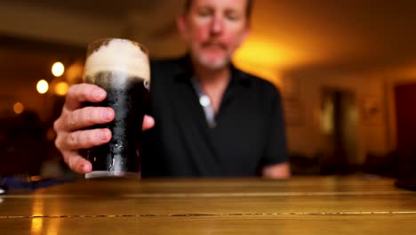 un hombre bebe cerveza fuerte en un pub.