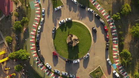 aerial orbit top view of roundabout with many parking and driving cars in colorful road during sunset time in cordoba city