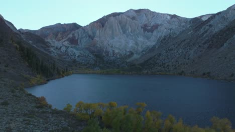 mammoth mountain lakes convict canyon lake aerial drone california autumn fall later afternoon shaded rugged valley peaks yellow aspen birch trees clear skies sierra nevadas circle right motion windy
