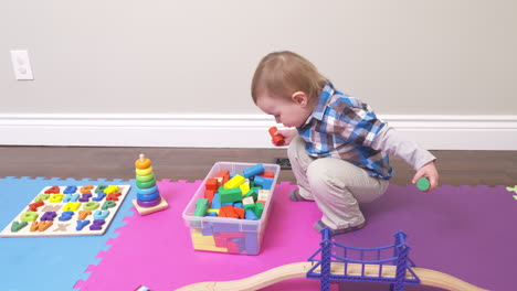 inquisitive toddler boy playing with his blocks and other toys