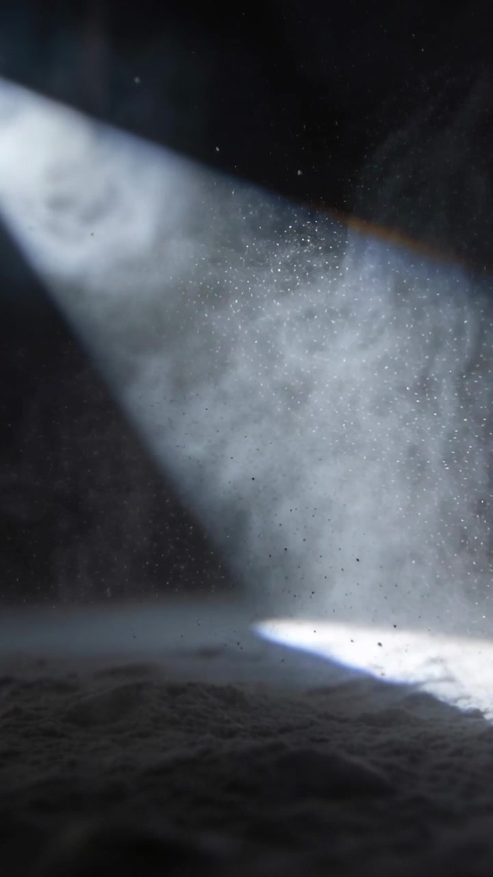 Vertical video: Entering upper-left beam carrying swirling dust over cellar floor, revealing specks