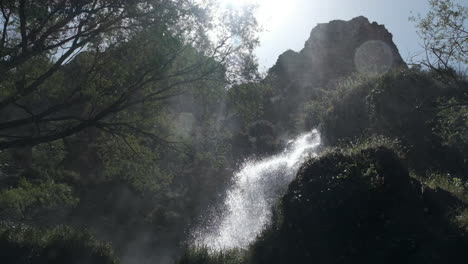 bright waterfall in a lush mountain landscape with sunlight