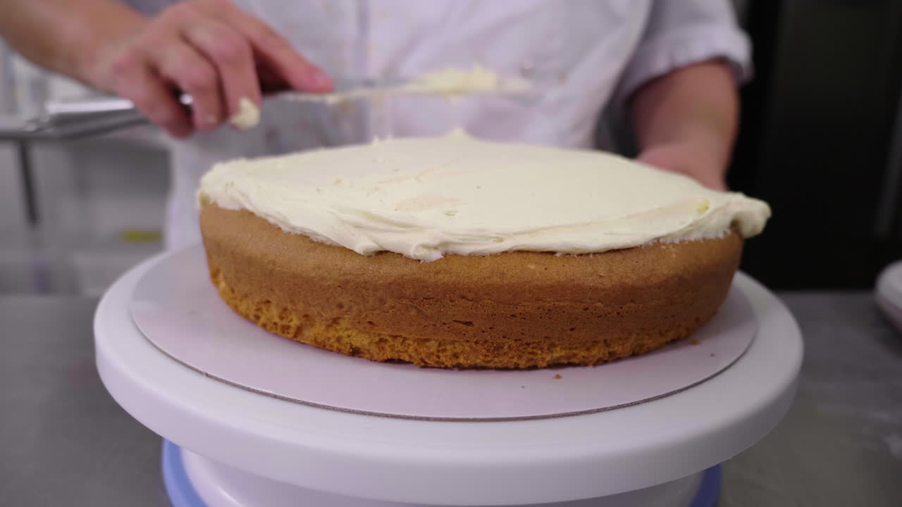 A plain sponge cake is iced with thick buttercream