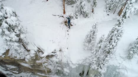 Ice-climber-standing-at-top-of-frozen-cliff-4k