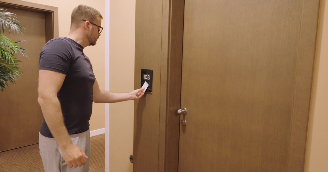 ホテルキーカードを使ってホテルの部屋のドアのロックを解除し開ける男性。ホテルへのアクセス、宿泊、ゲストチェックイン、部屋のセキュリティに関する旅行コンセプト。