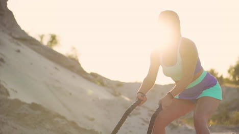 hermosa atleta en una carrera de arena de pie con cuerdas haciendo ejercicio en el sol de pie en la arena.