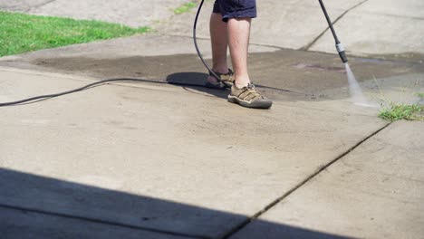 man pressure washing dirty concrete in the heat-1