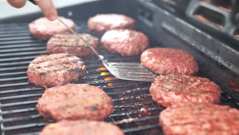 lid opening on grill and spatula flipping alternative meat burger patties on a barbecue, wide shot panning with flame in 60 frames per second 4k