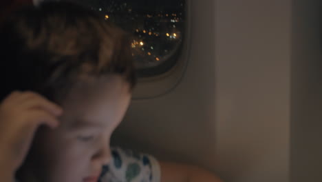 niño cansado está esperando el viaje aéreo para terminar él usando almohadilla para pasar el tiempo