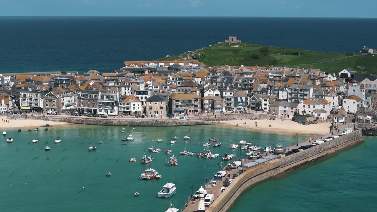 Ascending pan down aerial of turquoise St Ives bay with boats floating at high tide
