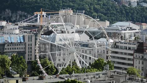 general shot of the city with a spinning wheel and a forest in the background