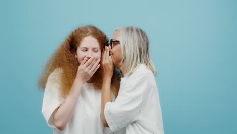 a woman whispering a secret to her daughter