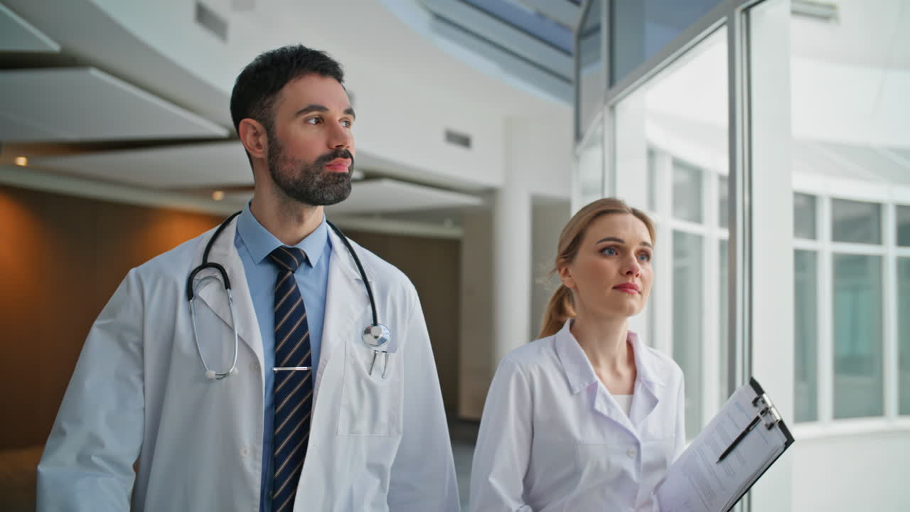 Primo piano di due medici che camminano in ospedale salutando un collega. Squadra medica unita.