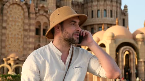 turista hablando por teléfono mientras está sentado en la mezquita de hierba, india